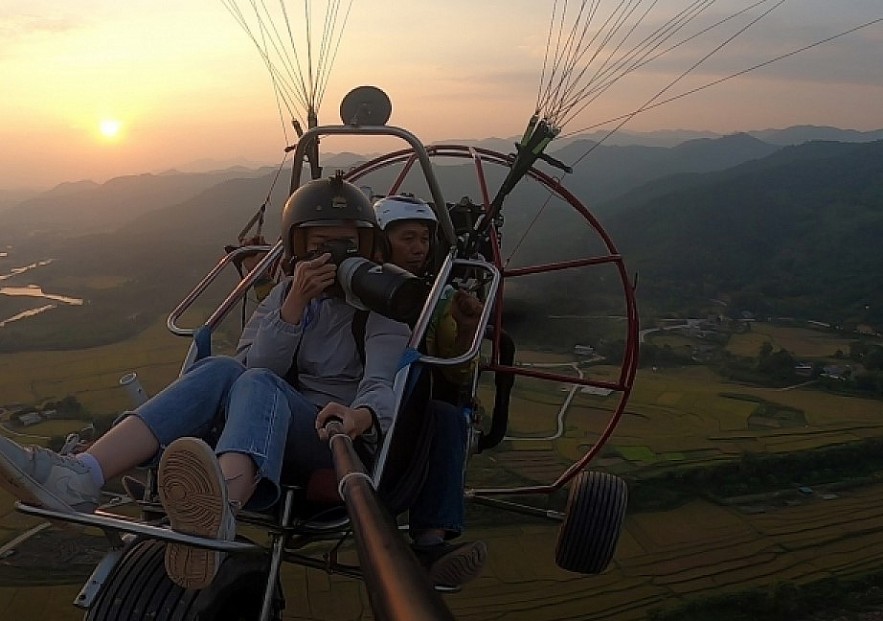 Paragliding over golden rice terrace fields in Northern Vietnam