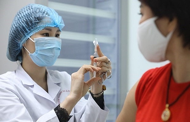 A health worker prepares to administer COVID-19 vaccine to a woman. Photo: VNA