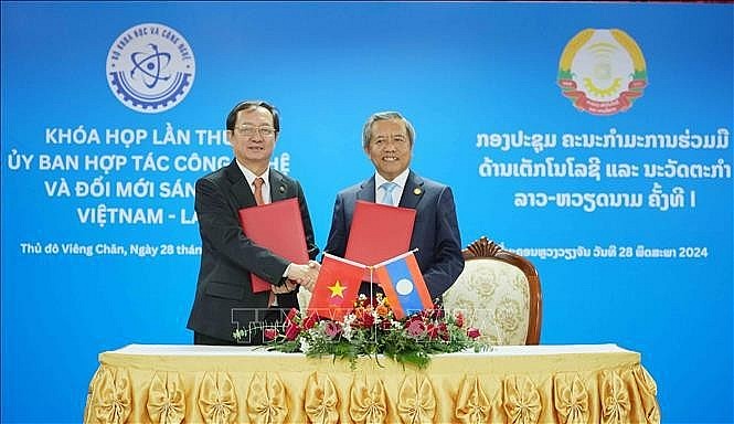 Vietnamese Minister of Science and Technology Huynh Thanh Dat (L) and Lao Minister of Technology and Communications Boviengkham Vongdara exchange the minutes of the first session of the Vietnam-Laos Committee for Cooperation in Technology and Innovation in Vientiane, Laos, on May 28. (Photo: VNA)
