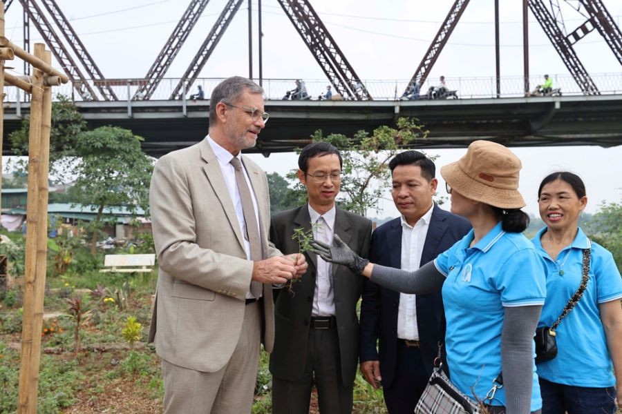 The French Ambassador engages in discussions with residents about the playground located at the base of Long Bien Bridge and the various plants and herbs cultivated nearby.