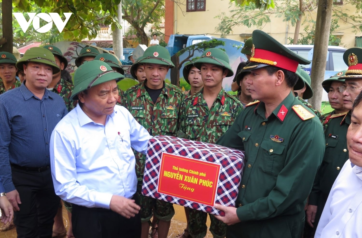 PM phuc highlights the great efforts put in by relevant forces from ministry of national defence and public security as they participate relief rescue to protect lives property local citizens. pictured is pm presenting gifts officers soldiers military region 4