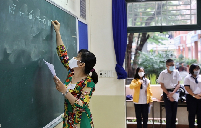 Unprecedented National Graduation Examination in Vietnam An examiner writing the time allowance onto the blackboard before the exam begins