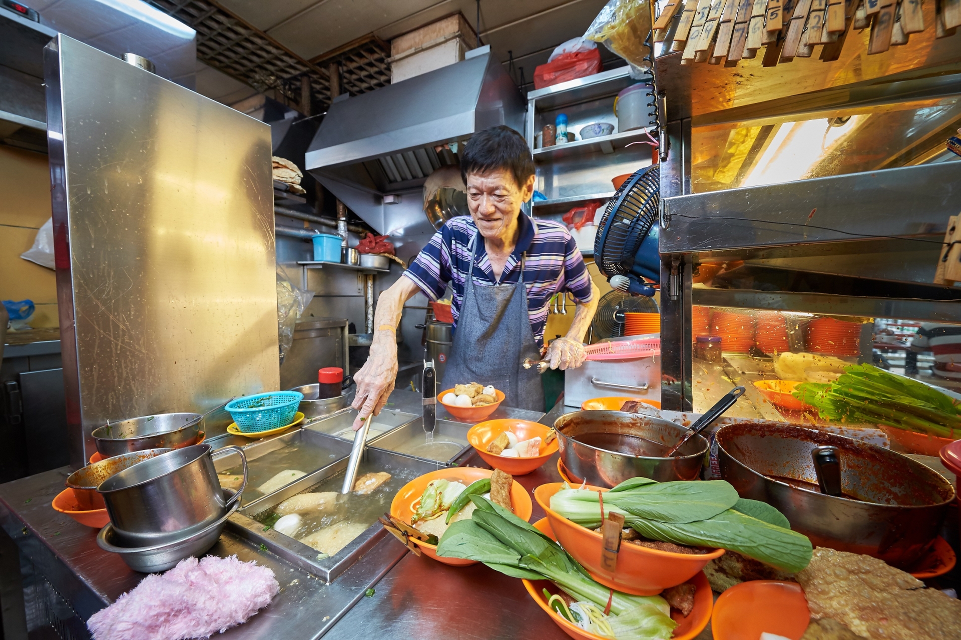 A Singaporean vendor making food at his hawker (Photo: Oursg Heritage)  