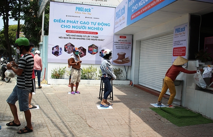 Vietnamese people waiting in line for their turn to get rice from the dispensing machine (photo: vne) 