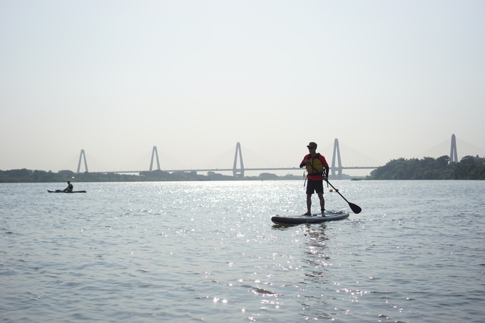 Young people in Hanoi try paddle boarding on Red river