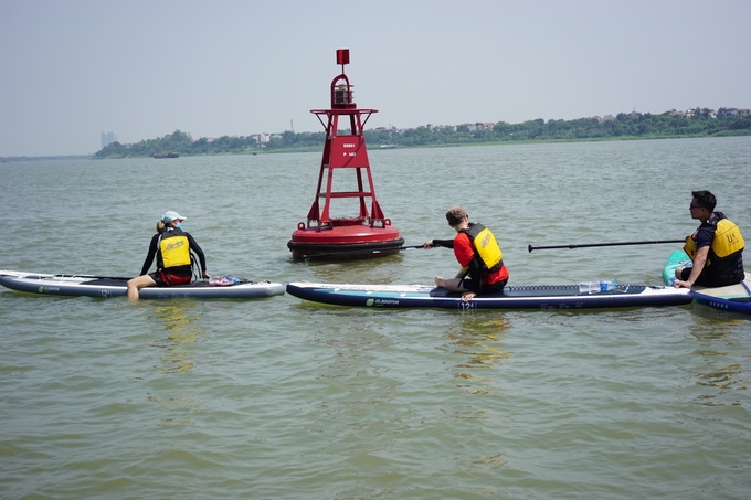 Young people in Hanoi try paddle boarding on Red river