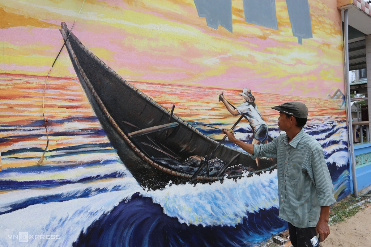 Artist Pham Dinh Hai is drawing a mural with 15m in length and 5m in width on the wall of a local house. His painting features coastal village’s residents riding boats to catch fish.