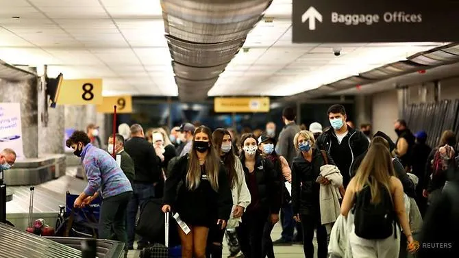 Travelers wearing protective face masks to prevent the spread of COVID-19 reclaim their luggage at the airport in Denver, Colorado, US on Nov 24, 2020. (Reuters/Kevin Mohatt)