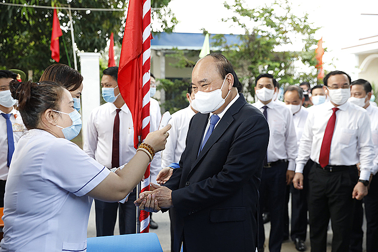 President Nguyen Xuan Phuc has his body temperature checked and his hands disinfected prior to the voting process in Cu Chi Town.