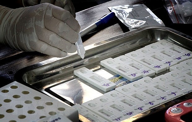 A medical worker places drops of liquid sample into a Covid-19 indicator device. Photo: VNA