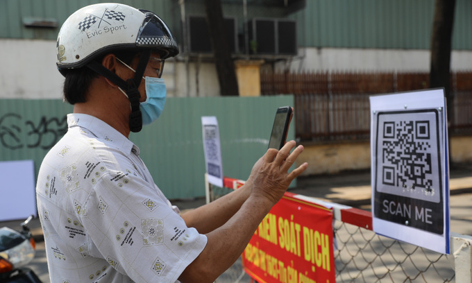 A man scans a QR code to complete the health declaration, one of the procedures everyone has to complete to get through Covid-19 checkpoints in Go Vap District, now the biggest Covid hotspot in HCMC, June 3, 2021. Photo: VnExpress