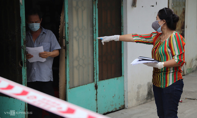 An official guides a man on protocols he should follow to quarantine himself at home in HCMC, February, 2021. Photo by VnExpress/Dinh Van.